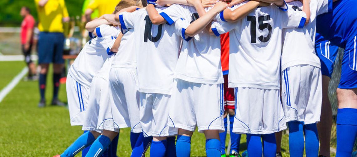 53762250 - coach giving young soccer team instructions. youth soccer team together before final game. football match for children. boys group shout team, gathering. coach briefing. soccer football background.