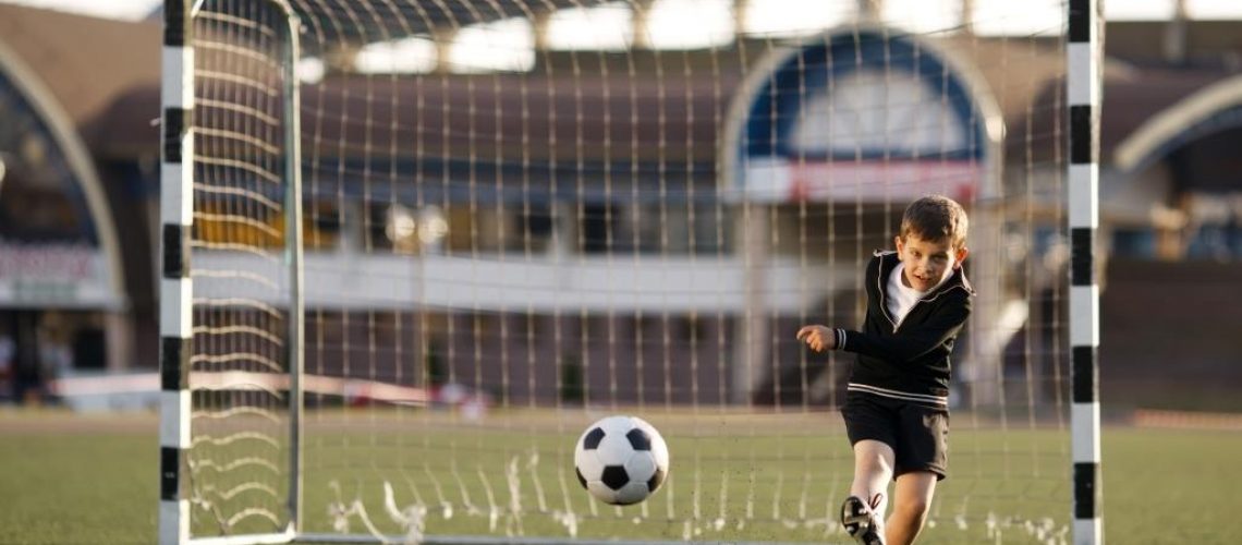 boy-plays-football-on-stadium-PR5MN7C