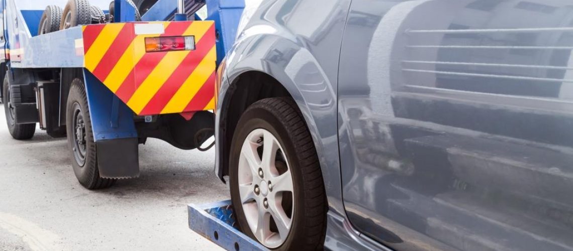 Tow truck towing a broken down car on the street