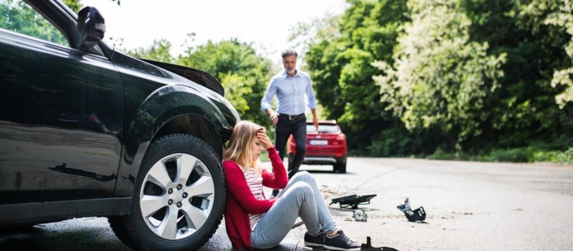 Young frustrated woman by the car after an accident and a mature man running towards her.